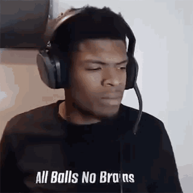 a man wearing headphones and a microphone with the words `` all balls no brains '' written on it .