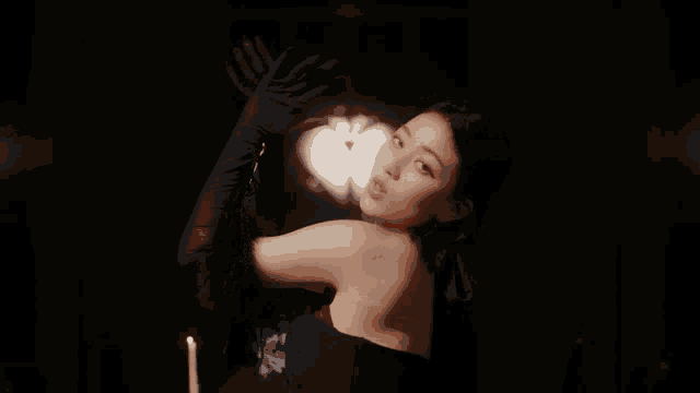 a woman wearing black gloves is standing in front of a table with a candle