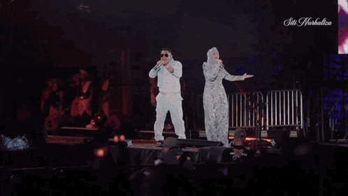 a man and a woman are singing on a stage with fireworks in the background and the words sin herbalife on the bottom