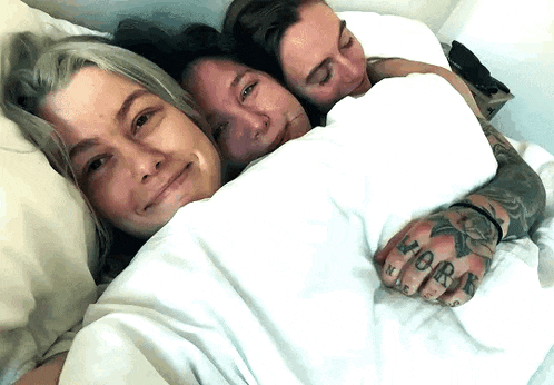 a man with a tattoo on his hand is laying with two women