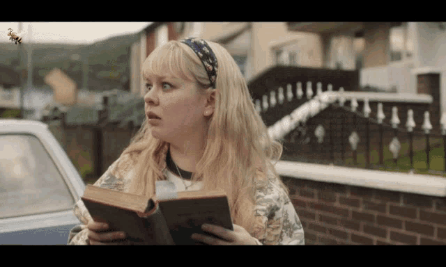 a woman holding a book with a bee flying overhead