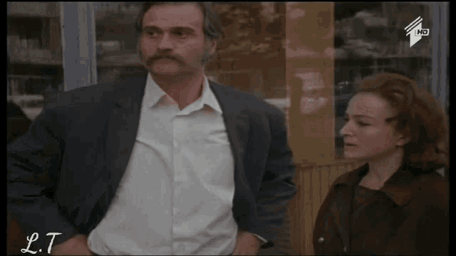 a man in a suit is talking to a woman in a blurry photo with lt written on the bottom