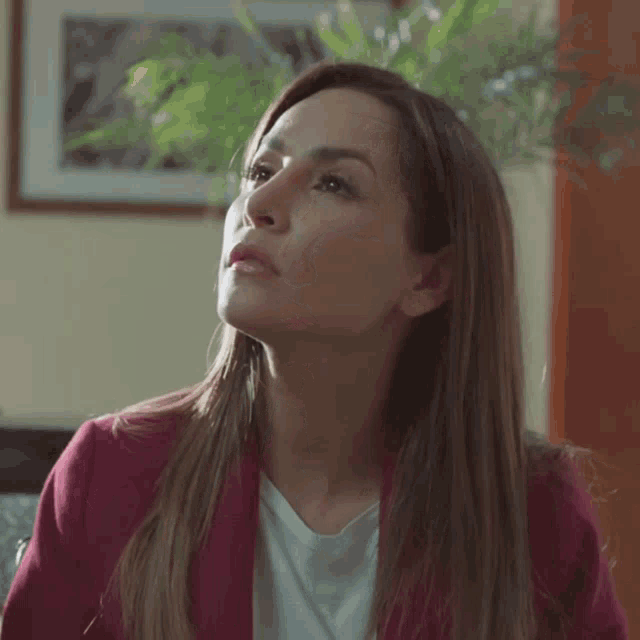 a woman wearing a red jacket and white shirt looks up