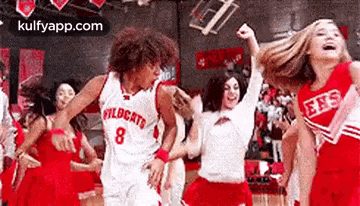 a basketball player and cheerleaders are dancing on a basketball court .