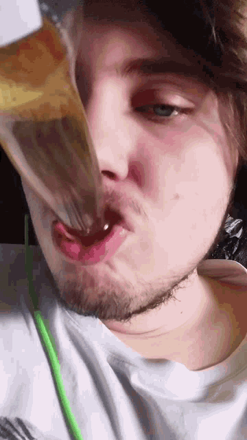 a man with a beard is drinking from a bottle with a green straw
