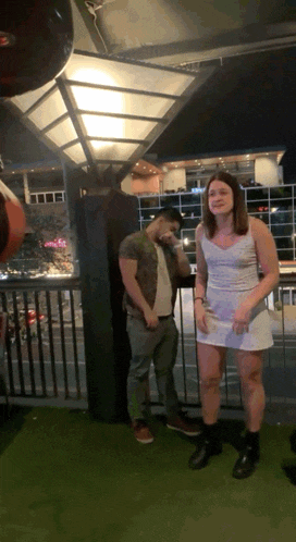 a woman in a white dress is standing next to a man in a green shirt