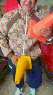 a person wearing a gucci jacket holds a yellow cone