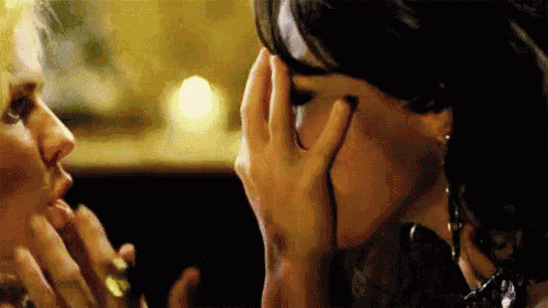 a woman is covering her face with her hand while a man looks on .