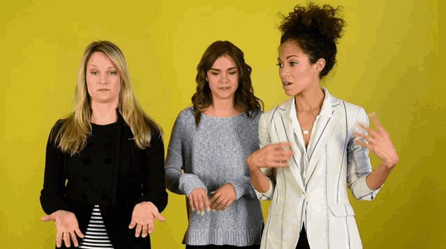 three women standing next to each other with their hands in their pockets