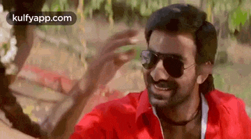 a man in a red shirt and sunglasses is smiling at a woman .