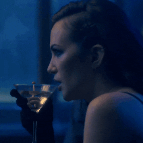 a woman is drinking a martini in a glass