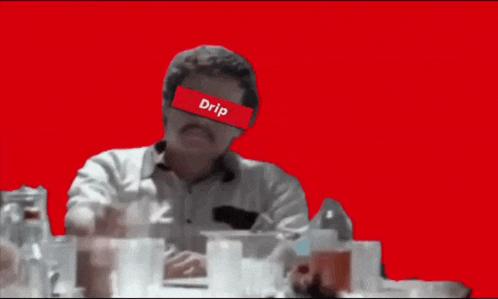 a man is sitting at a table with a red background and a drip sticker on his face