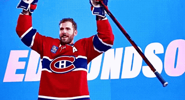 a hockey player in a red white and blue jersey is holding a hockey stick