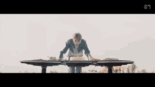 a man in a blue suit is kneeling down at a table with a cake on it