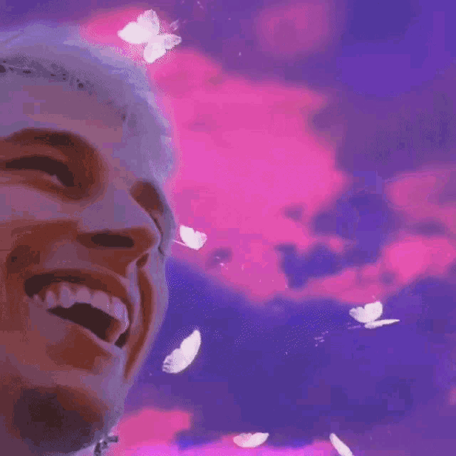 a close up of a person 's face with butterflies flying around him