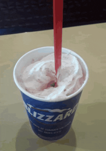 a cup of blizzard ice cream with a red straw in it