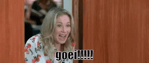 a woman in a floral shirt is standing in a doorway and making a funny face .