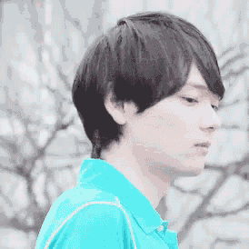 a young man in a blue shirt is looking down at something