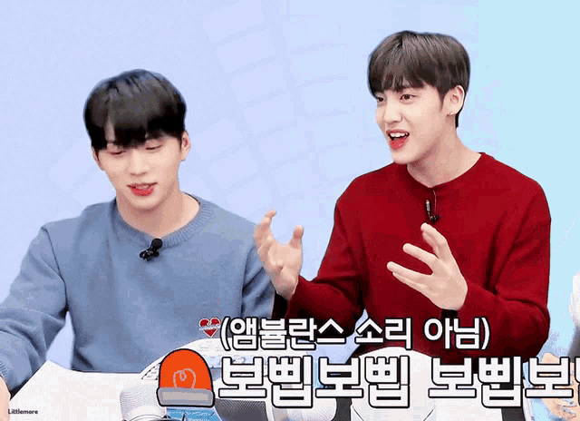 two young men are sitting next to each other and one of them is wearing a red sweater with korean writing on it