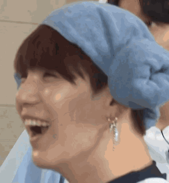 a close up of a person wearing a blue towel around their head and smiling .