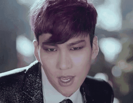 a man with purple hair is wearing a suit and tie .