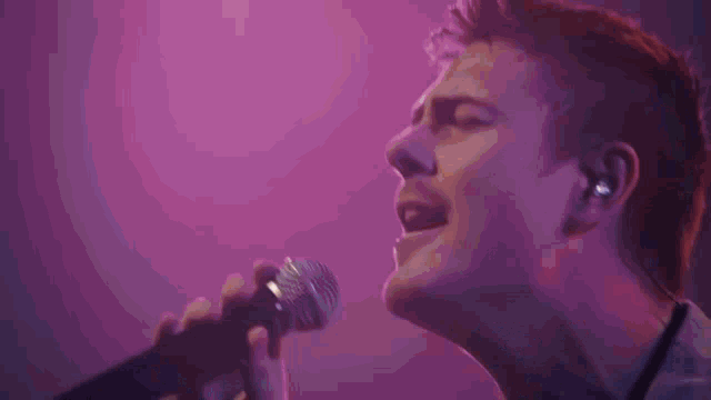 a man is singing into a microphone with his hands outstretched .
