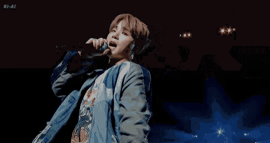 a man is singing into a microphone on stage .