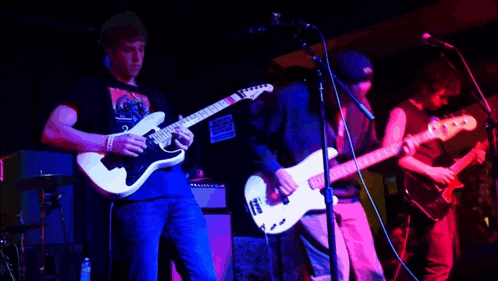 a man playing a guitar in front of a microphone with a sticker on his shirt that says ' a '