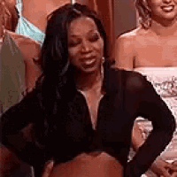 a woman wearing a black crop top is standing in front of a group of women .