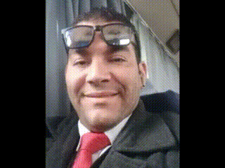 a man wearing glasses and a red tie smiles at the camera