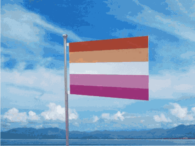 a lesbian flag is flying in front of a blue sky