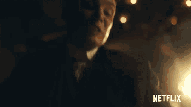 a man in a suit and tie is in a dark room with a netflix logo behind him