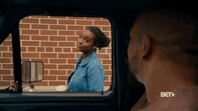 a man and a woman in a car with a bet logo on the bottom right