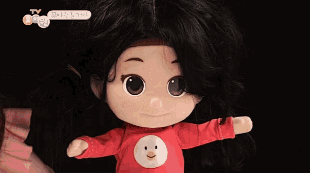 a doll wearing a red shirt with a smiley face on the front