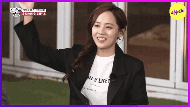 a woman wearing a black jacket and a white shirt that says in a life