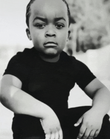 a black and white photo of a young boy in a black t-shirt