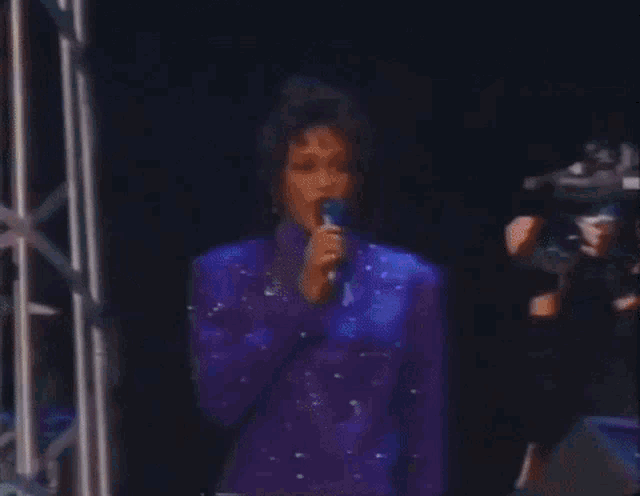 a man in a purple suit is holding a flag in front of a crowd