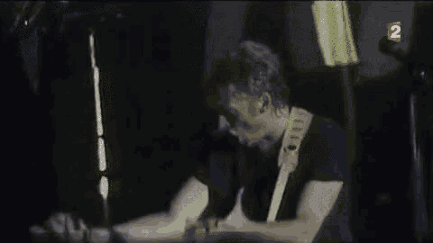 a man is playing a guitar in a dark room with the number 2 on the bottom