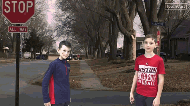 two boys standing in front of a stop sign and a sign that says all way