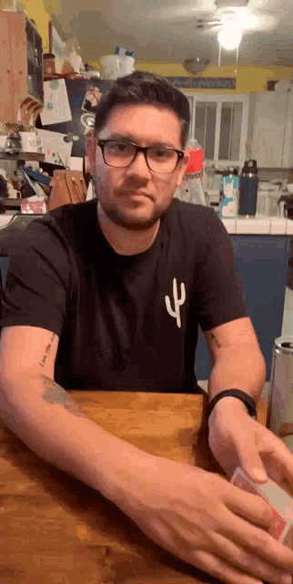 a man wearing glasses and a black shirt with a cactus on the front
