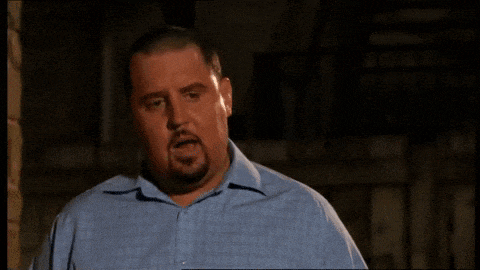 a man with a beard and a blue shirt is making a funny face