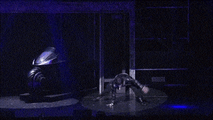 a person is doing a trick on a stage with a motorcycle in the background .