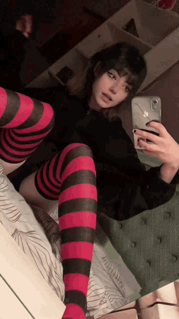 a girl wearing red and black striped knee high socks is taking a selfie