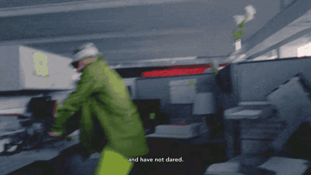 a man in a green shirt and yellow pants is standing in an office with the words " and have not dared " written below him
