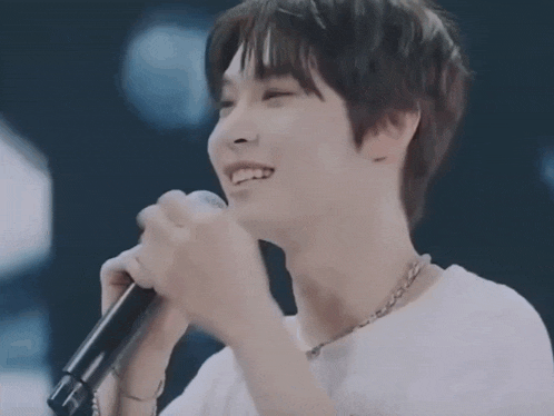 a man is singing into a microphone and smiling