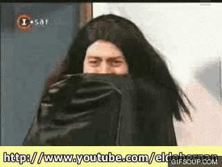 a man with long hair is covering his face with a black cloth and the website is http://www.youtube.com