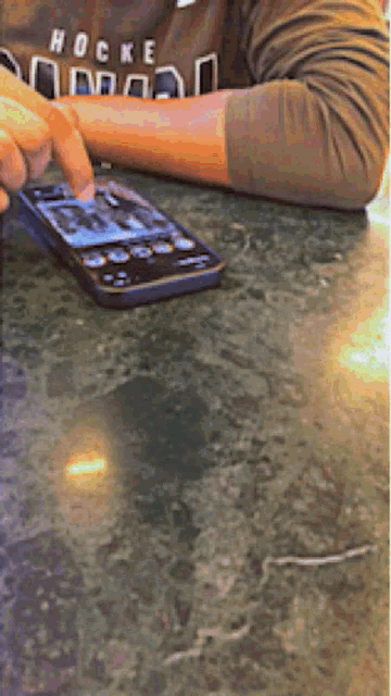 a person wearing a shirt that says hockey is using a smart phone