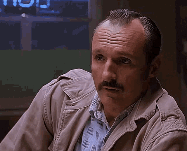 a man with a mustache is wearing a jacket and a plaid shirt