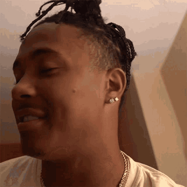 a close up of a man 's face with his eyes closed and earrings