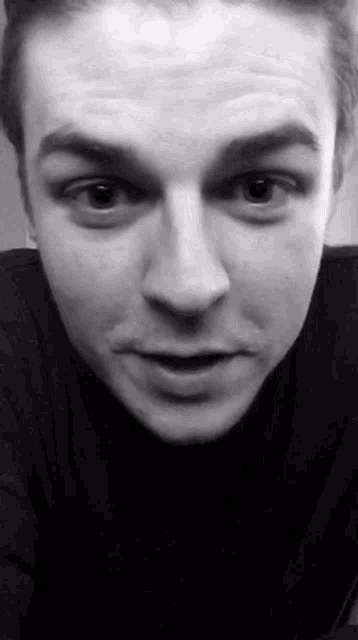 a close up of a man 's face in a black and white photo with his mouth open .